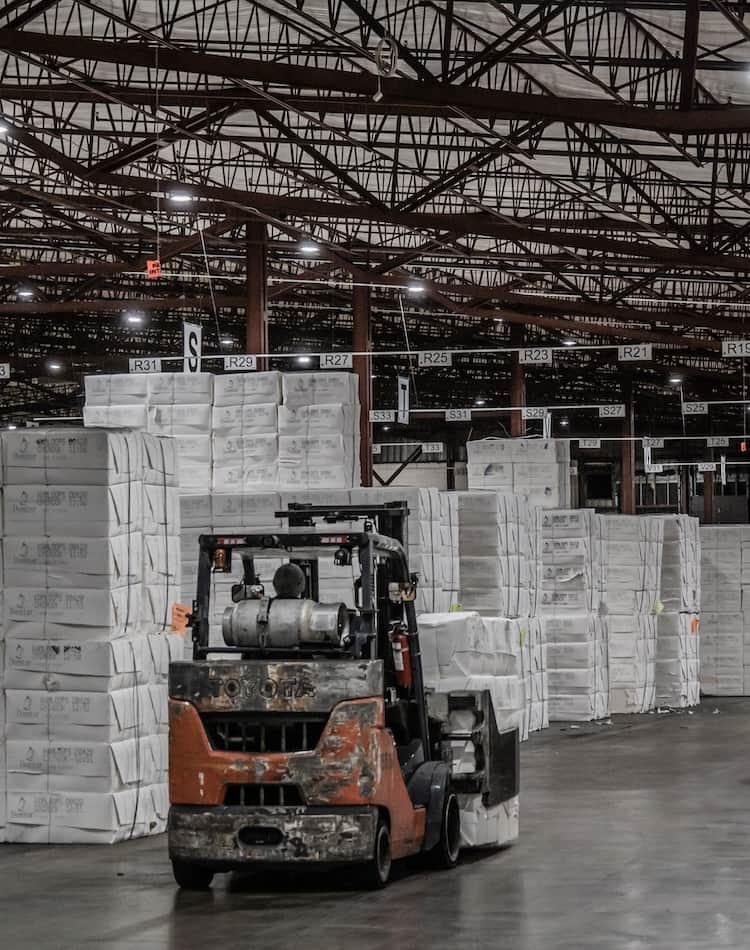 WTC worker moving pulp in a warehouse using heavy equipment