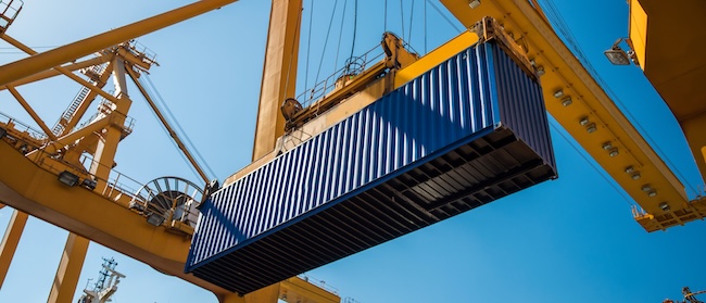 large blue shipping container being lifted by machinery in port shipping container logistics area. 