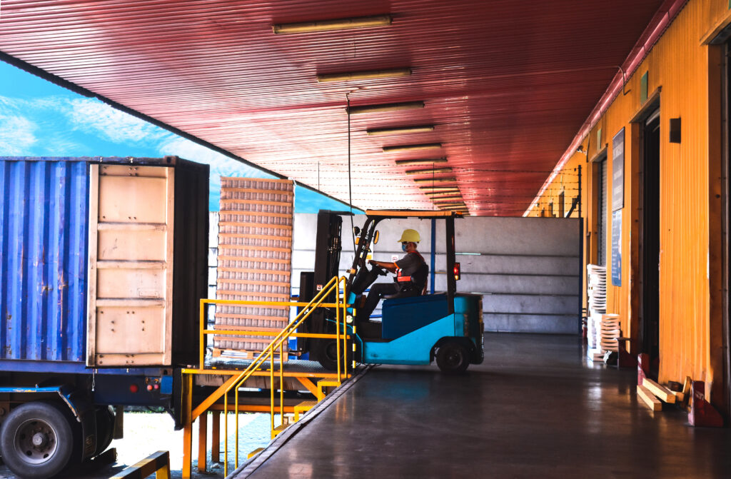 Forklift Unloading Palletized Cargo from Shipping Container at Dock